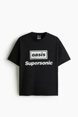 Remera negra de algodón con cuello redondo, mangas cortas y hombros caídos. Cuenta con un estampado frontal que dice "oasis" dentro de un rectángulo y la palabra "Supersonic" debajo.