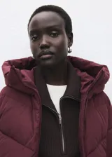 Campera acolchada de corte recto y diseño puffer, color bordó. Cuenta con capucha, cuello alto, cierre frontal de cremallera doble y dos bolsillos laterales con cierre. Presenta mangas largas con puños elásticos y acabado repelente al agua.