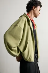 Cazadora relaxed fit de hombre, confeccionada en tejido estructurado tipo waffle con efecto lavado en color verde. Cuenta con cuello con capucha, cierre frontal con cremallera, bolsillos frontales tipo canguro y acabados elásticos en puños y bajo.