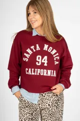 Sweater bordó de corte clásico con estampa frontal con la leyenda 'Santa Monica 94 California' en color blanco.