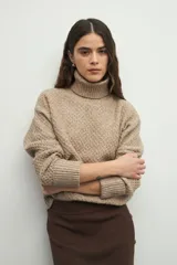 Polera de cuello alto con textura tramada, manga larga con puños acanalados y diseño holgado.