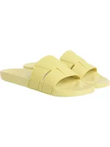 Ojotas tipo slide de Calvin Klein, color amarillo pálido. Presentan una suela moldeada ergonómica con soporte para el arco plantar y una capellada de doble tira de TPU con diseño en relieve y el logotipo de Calvin Klein grabado.