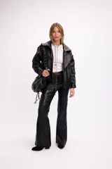 Pantalón de tiro alto confeccionado en cuerina negra, con corte oxford y diseño ajustado en la parte superior que se ensancha hacia el ruedo.