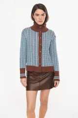Cardigan de punto con patrón trenzado, color crudo y visón, con cuello solapa, cierre frontal de botones y mangas largas con puños elásticos rayados.