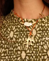 Collar con dije de bronce macizo con forma orgánica irregular, similar a un coral, suspendido de un cordón negro de seda natural anudado.