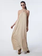 Vestido largo color beige con cuello halter regulable.