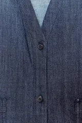 Camisa de tejido tipo denim azul oscuro, con escote pico, manga corta ancha y dos bolsillos de parche frontales. Cierre frontal con botones.