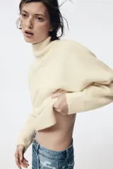 Jersey de punto liso con cuello subido, manga larga y detalle de costura vertical marcada en el frente. Presenta terminaciones en rib en puños, cuello y ruedo.