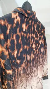 Blazer entallado con hombreras, con un diseño que combina estampado de leopardo en la parte superior y degradado de piel de serpiente en la inferior.