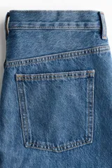 Minifalda de denim azul con diseño clásico de cinco bolsillos, trabillas para cinturón y cierre frontal con botón y cremallera.