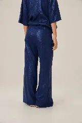 Pantalón de lino azul metalizado, de corte ancho y recto, con cintura elástica y bolsillos traseros.