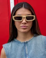 Lentes de sol rectangulares con montura gruesa color beige y cristales negros.