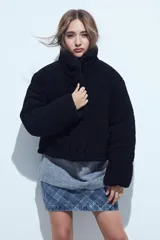 Campera puffer de corderito negro con cuello alto y diseño oversized. Presenta una textura tipo teddy, cierre frontal y corte a la cintura.