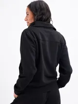 Campera de felpa con cierre frontal completo, cuello alto y bolsillos laterales. Presenta puños y ruedo acanalados, con costuras decorativas que definen la silueta.
