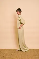 Pantalón palazzo de satén color verde, de tiro alto y corte amplio con bolsillos laterales.