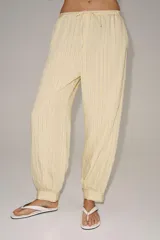 Pantalón bombacho de tiro medio, confeccionado en hilatura con mezcla de viscosa, con estampado de rayas verticales en tonos beige y amarillo claro, cintura elástica ajustable con cordón y puños en los tobillos.