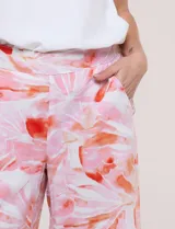 Pantalón crop de lino y rayón, con diseño wide leg de corte holgado, estampado tropical de hojas en tonos verde, azul y marrón sobre fondo blanco. Cuenta con pretina trasera elastizada y bolsillos delanteros.