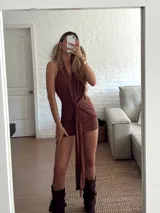 Vestido corto color marrón, con escote halter profundo y detalle de nudo frontal con caída larga. Diseño ajustado al cuerpo.