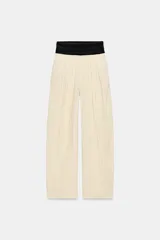 Pantalón de tiro medio Zara Woman Collection, con fajín negro a contraste, pliegues delanteros, pernera ancha, bolsillos laterales ocultos y cierre lateral con cremallera.