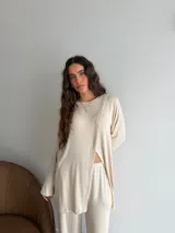 Conjunto de dos piezas color gris melange, confeccionado en tela de lanilla, compuesto por un buzo de manga larga con diseño cruzado al frente y un pantalón largo de corte holgado y tiro alto.