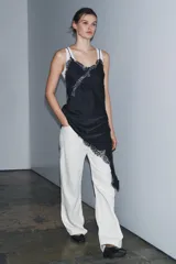 Vestido corto de satén con escote en pico y tirantes finos. Presenta aplicaciones de encaje en el escote y en el bajo, con un diseño asimétrico y abertura lateral.