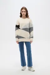 Sweater de tejido de punto con diseño geométrico color block en tonos beige, gris y negro, de corte holgado, cuello redondo y manga larga.