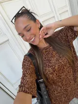 Conjunto de dos piezas compuesto por una remera de manga corta y un pantalón de corte acampanado, ambos confeccionados en lanilla con estampado animal print en tonos marrones.