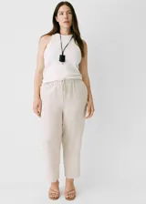 Pantalon de lino color beige, de corte recto y tiro alto. Cuenta con cintura elástica con cordón ajustable y bolsillos laterales.