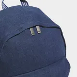 Mochila Adidas de estilo clásico confeccionada en tejido de sarga de algodón color azul denim. Cuenta con un compartimento principal amplio, bolsillo frontal con cierre, bolsillos laterales elásticos y correas ajustables acolchadas con detalle de rayas. Presenta el logotipo del trébol de la marca en la parte inferior frontal.