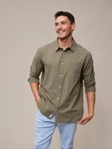 Camisa de manga larga color verde oliva, confeccionada en algodón con efecto peach (suave al tacto). Presenta cuello camisero, cierre frontal de botones y un bolsillo de parche en el pecho izquierdo.