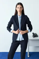 Blazer clásico de corte entallado en color negro, con solapas tradicionales, cierre frontal de un botón y mangas largas con detalle de botones en los puños.