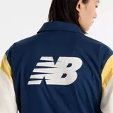 Campera New Balance Athletics Varsity azul marino con mangas color crema y detalles amarillos en los hombros. Logo de New Balance bordado en el pecho.