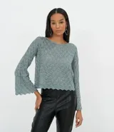 Blusa de punto color verde con textura geométrica, cuello redondo y mangas largas acampanadas con terminación ondulada.