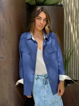 Chaqueta azul de manga larga con cuello camisero, cierre con botones y bolsillos frontales.