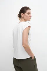 Blusa blanca con bordados florales y broderie en el frente, de manga corta y corte recto.
