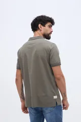 Chomba de piqué en color negro, de manga corta, con cuello y puños tejidos con líneas a contraste. Presenta cierre frontal parcial con botones y pequeño logo bordado en el pecho.
