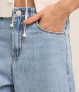 Bermuda tipo jorts de tiro alto confeccionada en denim de algodón, con diseño de cinco bolsillos, trabillas para cinturón y cierre frontal con botón y cremallera.