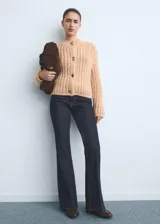 Pantalón de jean estilo flare con tiro alto, confeccionado en tejido de algodón con elasticidad. Presenta diseño de cinco bolsillos, cierre de botón y cremallera, y trabillas para cinturón.