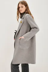 Tapado negro de corte recto y largo medio, con solapas clásicas, cierre frontal de un botón y bolsillos laterales amplios.