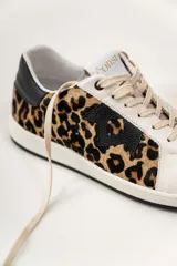 Championes de cuero color blanco con detalle de corona en animal print y talón verde. Cuentan con suela de caucho, lengüeta de gamuza y forro textil, con cierre mediante cordones al tono.