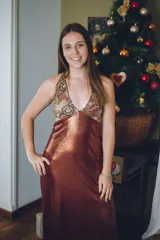 Vestido largo con estampado tie-dye en tonos violeta y fucsia, escote en V con detalles bordados dorados, cut-outs laterales bajo el busto y tirantes finos que se cruzan y atan en la espalda.