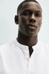 Camisa negra de lino y algodón, corte relaxed fit, cuello mao, manga larga con puños abotonados y cierre frontal con botones.