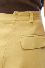 Pantalón de lino color tostado, de tiro alto y corte amplio con perneras rectas. Cuenta con pasacintos, bolsillos laterales y bolsillos traseros con solapa.