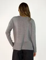 Sweater de punto color negro, con cuello redondo, manga larga y diseño con costura central vertical. Presenta un dobladillo acanalado en la cintura y puños, con un largo asimétrico siendo más corto en la parte delantera y más largo en la parte trasera.