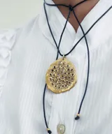 Collar con cordón de cuero marrón y dije circular de plata con perforaciones.