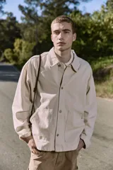 Camisa de denim color beige claro, corte amplio, cuello clásico, cierre frontal con botones y mangas largas. Confeccionada en tejido denim de sarga con acabado acid wash.