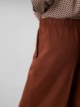 Pantalón cargo de corte relajado, confeccionado en una mezcla de lino y algodón. Presenta cintura elástica, bolsillos laterales y un diseño utilitario con un acabado en color marrón.