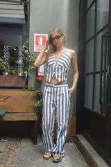 Top con cuello halter, a rayas verticales blancas y grises, con cierre frontal de botones.