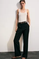 Pantalón de tiro alto color negro, de corte recto y pinzas frontales. Incluye un cinturón delgado de cuero marrón con hebilla metálica dorada.
