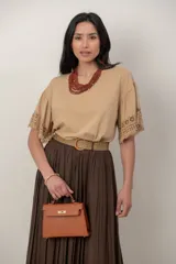 Cartera tipo bolso de mano de cuerina color suela, con herrajes metálicos dorados, asa corta superior y cierre con solapa y broche giratorio.
